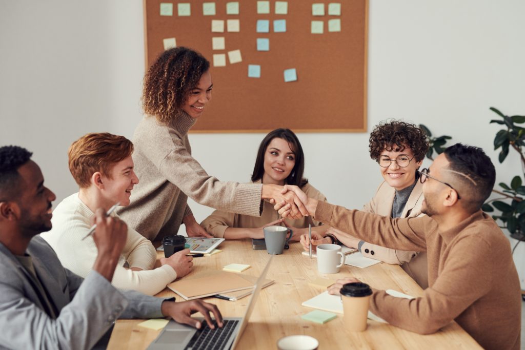 People meeting around a table, shaking hands.