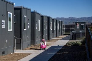 Shipping containers converted to homes line the perimeter of the Evans Lane interim housing facility located on city-owned land, in San José, on Jan. 30, 2023. (Beth LaBerge/KQED)